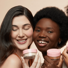 Duas mulheres segurando potes de maquiagem